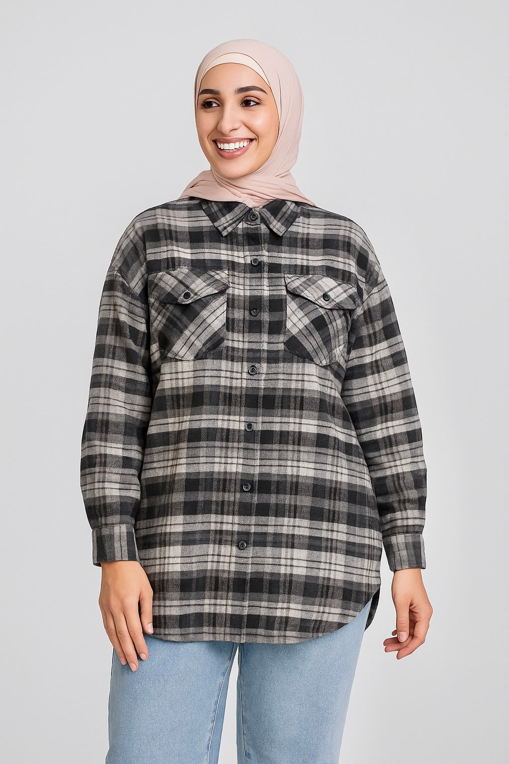 Woman wearing a plaid shirt and hijab on a plain background